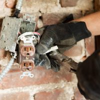 Man working on electric socket by brick wall